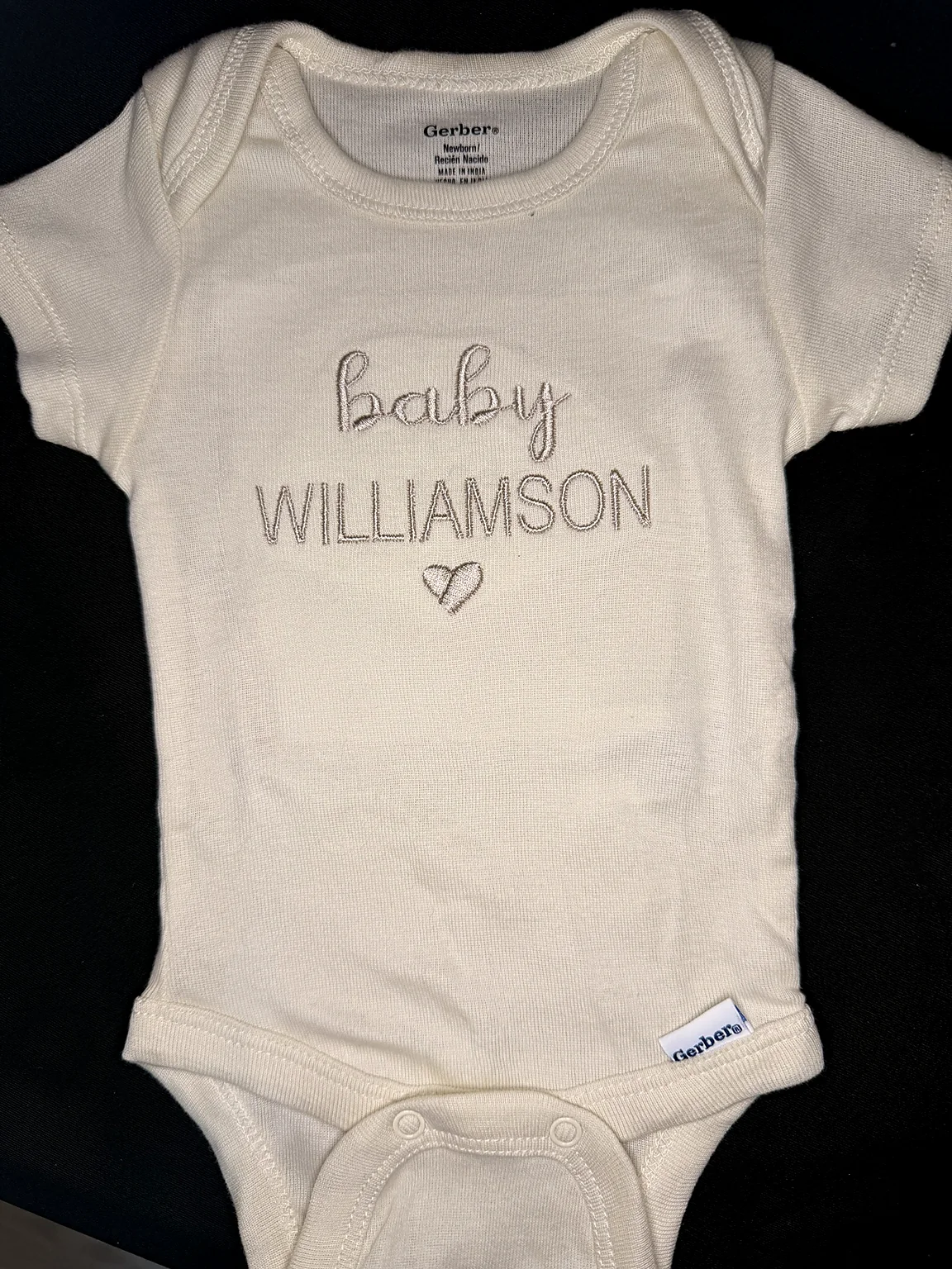 Cream baby bodysuit embroidered with Baby Williamson and a heart